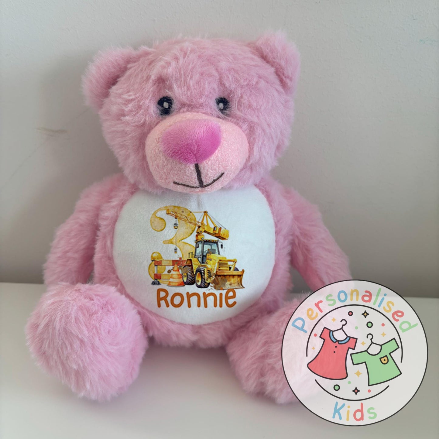 This adorable personalised teddy bear makes the perfect gift for little construction fans! The soft plush bear features a printed design with a yellow digger, crane, and traffic cones, along with your child’s name and age. A thoughtful keepsake that can be paired with our matching clothing range for a complete birthday gift set.