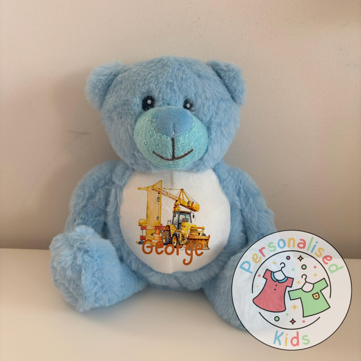 This adorable personalised teddy bear makes the perfect gift for little construction fans! The soft plush bear features a printed design with a yellow digger, crane, and traffic cones, along with your child’s name and age. A thoughtful keepsake that can be paired with our matching clothing range for a complete birthday gift set.