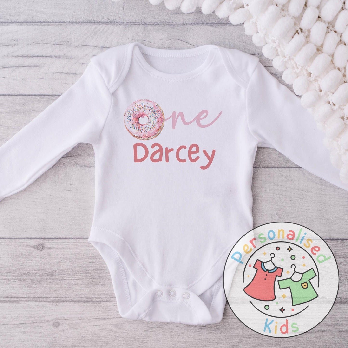 Make their first birthday extra sweet with this adorable personalised donut birthday outfit. Featuring the word “One” with a colourful sprinkle donut design in place of the “O”, and your child’s name personalised underneath, this outfit is perfect for birthday celebrations, cake smash photos, or as a keepsake to treasure.