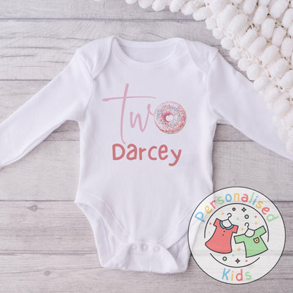 Make their 2nd birthday even sweeter with this adorable personalised donut birthday outfit! Featuring the word “Two” with a sprinkle donut design and your child’s name underneath, this cute top or baby grow is the perfect choice for a birthday celebration, cake smash, or as a special keepsake gift.